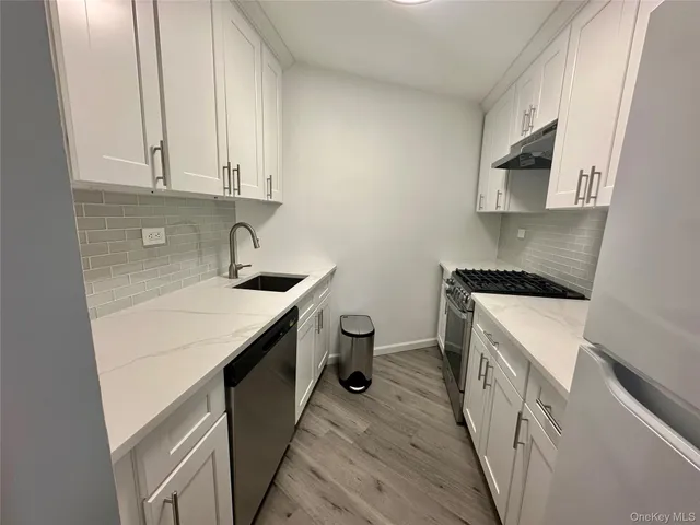 a kitchen with a sink dishwasher stove and white cabinets with wooden floor