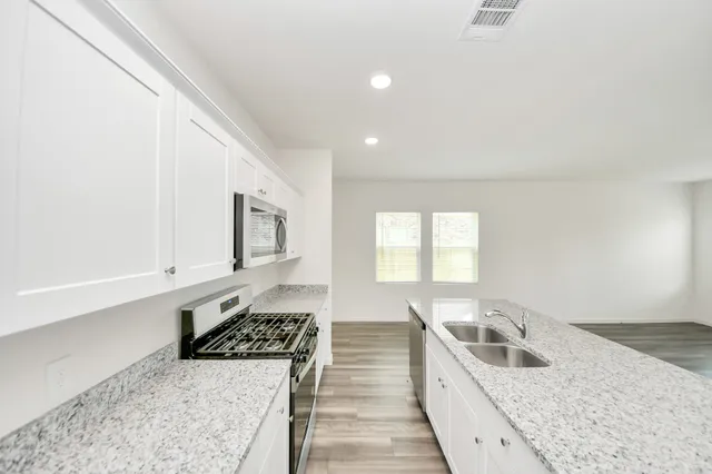 a view of kitchen with kitchen island stainless steel appliances wooden floor and window