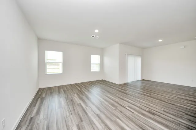 an empty room with wooden floor and windows