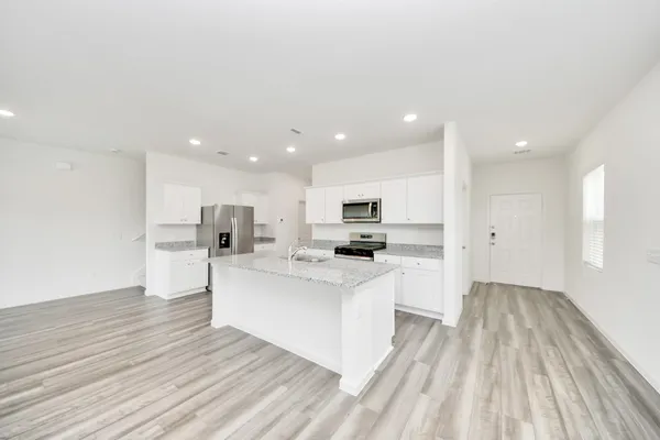 a large white kitchen with kitchen island a sink a center island stainless steel appliances and a counter space