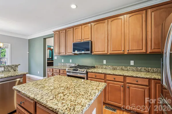 a kitchen with stainless steel appliances granite countertop wooden cabinets and a counter top space