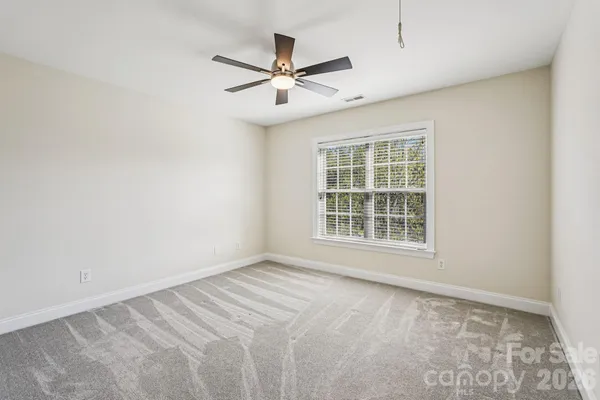 an empty room with window and ceiling fan
