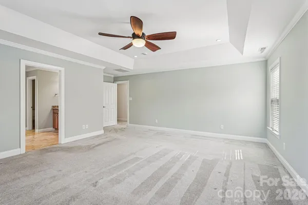 a view of an empty room with wooden floor and a ceiling fan