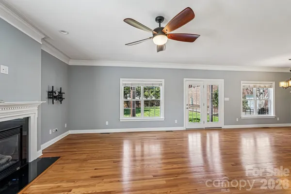 a view of an empty room with window and wooden floor