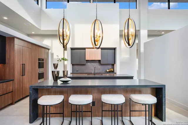 a kitchen with stainless steel appliances granite countertop a table chairs in it and wooden floors