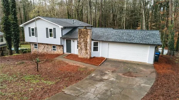 a view of a house with a yard and large tree