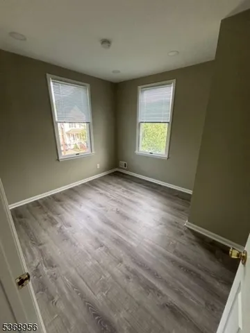 a view of empty room with wooden floor and kitchen