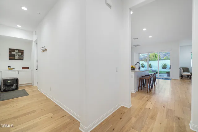 a kitchen with stainless steel appliances granite countertop a stove a sink a refrigerator a dining table and chairs with wooden floor