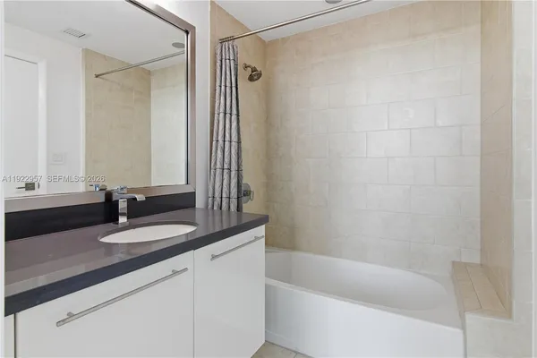 a bathroom with a granite countertop bathtub shower sink and mirror