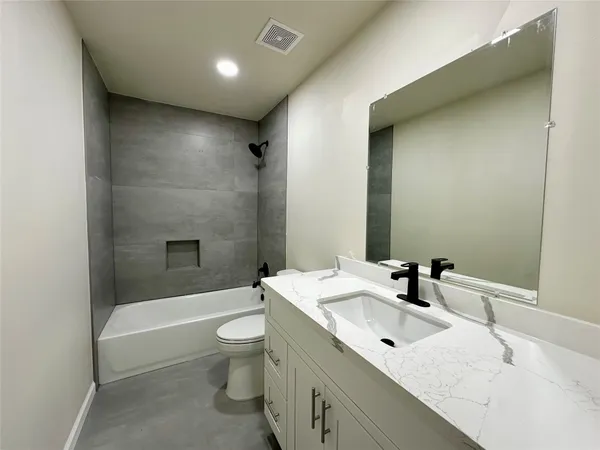 a bathroom with a bathtub toilet sink mirror and vanity