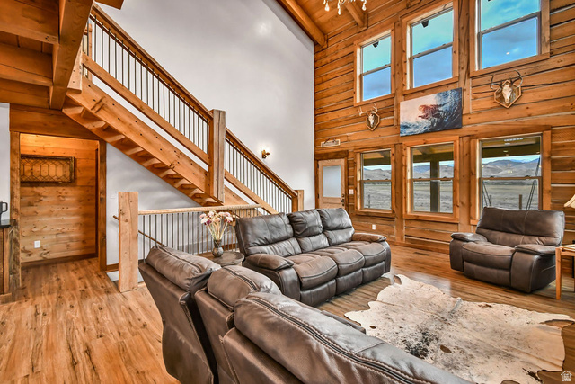 544 East 600 North, Unit 1 Joseph, UT 84739 - Photo 5 of 65 Vaulted ceiling living area featuring a prominent wood staircase with metal balusters, wood-finish flooring, and a log wall