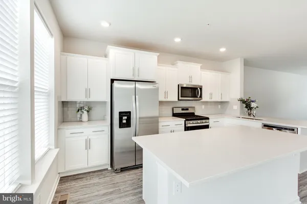a kitchen with stainless steel appliances white cabinets and a stove top oven