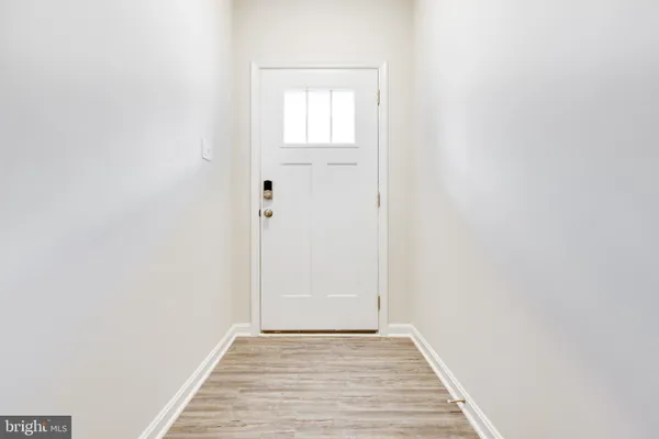 a view of an empty room with wooden floor and fan