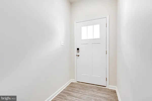 a view of an empty room with wooden floor and a ceiling fan