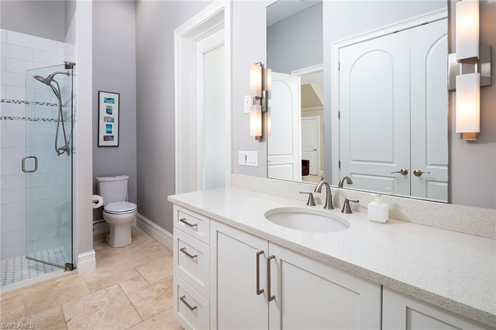 11617 Useppa Court Naples, FL 34110 - Photo 25 of 50 a bathroom with a granite countertop sink a toilet and a large mirror