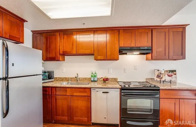 a kitchen with stainless steel appliances granite countertop a refrigerator stove top oven and sink