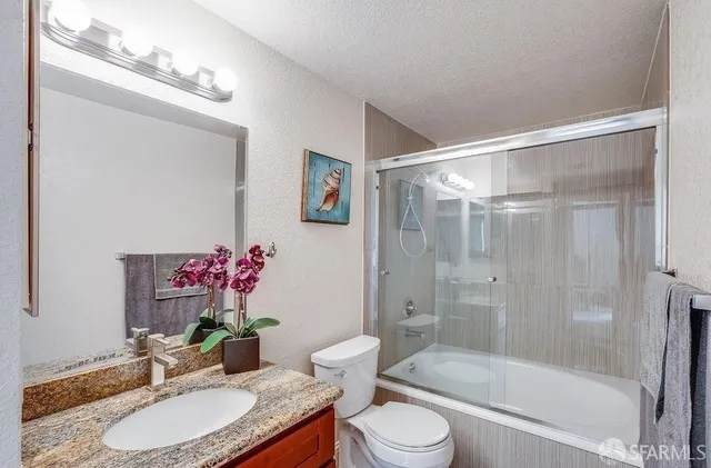 a bathroom with a granite countertop sink toilet a mirror and shower