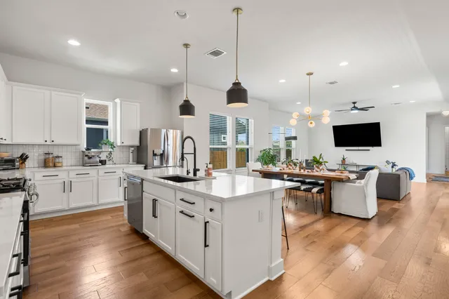 a kitchen with stainless steel appliances kitchen island granite countertop a stove a sink dishwasher a refrigerator and a dining table with wooden floor