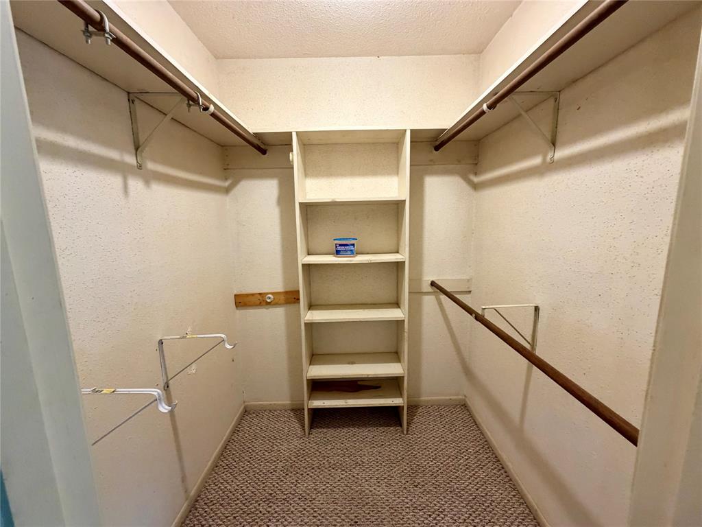 2030 Sycamore Street Paris, TX 75460 - Photo 9 of 24 Walk-in closet with integrated shelving unit, multiple hanging rods, and textured wall finish