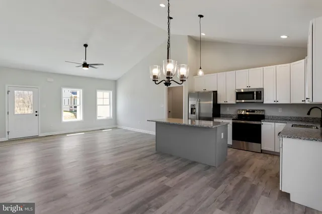 a kitchen with stainless steel appliances granite countertop a refrigerator a sink dishwasher a stove and white cabinets with wooden floor