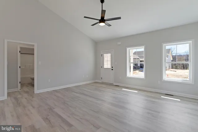 a view of an empty room with a window and wooden floor