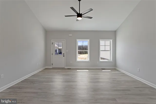 a view of an empty room with window and wooden floor
