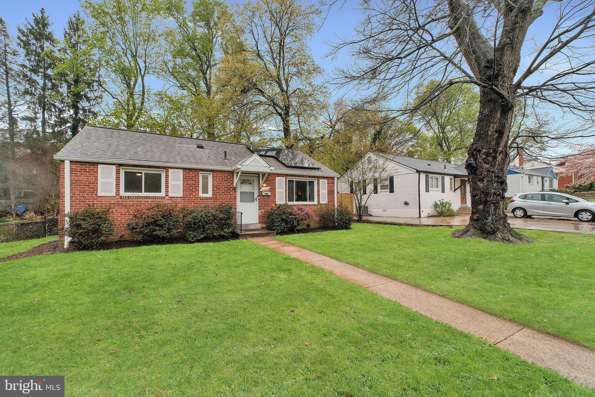 a front view of a house with a garden and trees