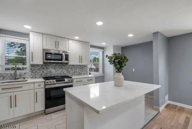 a kitchen with stainless steel appliances kitchen island a stove a sink a microwave and a refrigerator