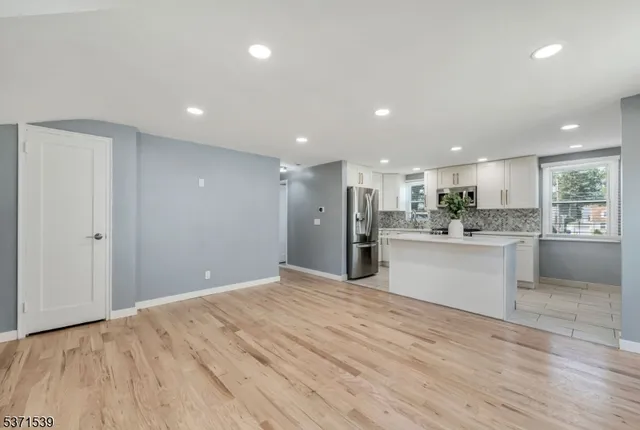 a view of kitchen with kitchen island wooden floor center island and stainless steel appliances
