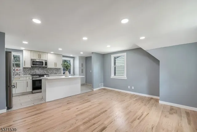 a large kitchen with kitchen island a sink dishwasher a stove and a refrigerator with wooden floor