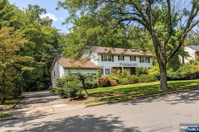 a view of a house next to a yard with potted plants and large trees