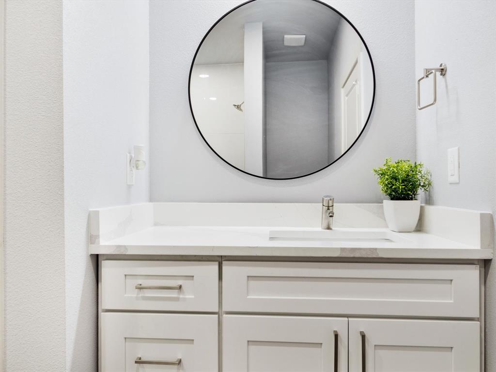 4705 Point La Vista Road Malakoff, TX 75148 - Photo 8 of 40 White shaker-style vanity with brushed nickel hardware, integrated rectangular sink, single-handle faucet, and round black-framed mirror