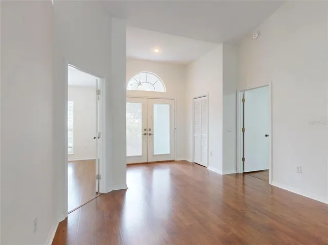 an empty room with wooden floor chandelier fan and windows
