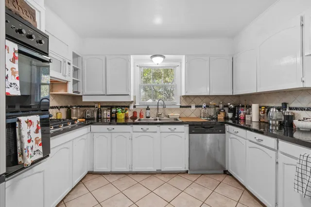 a kitchen with stainless steel appliances granite countertop a stove a sink and white cabinets