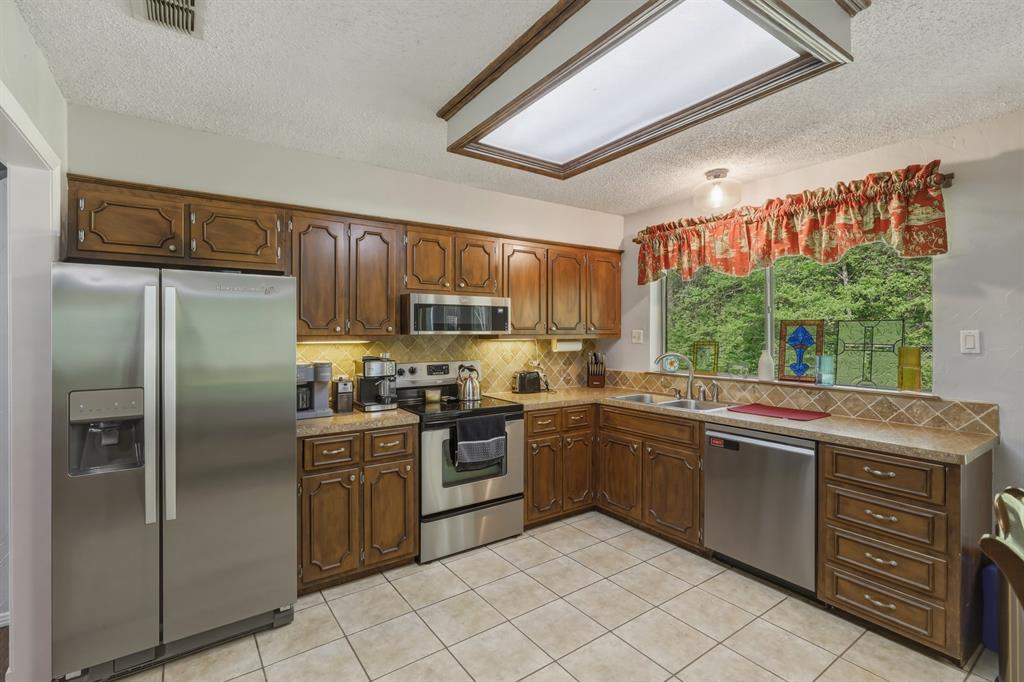 10203 Crestview Drive Tyler, TX 75707 - Photo 7 of 25 a kitchen with stainless steel appliances granite countertop a stove sink and refrigerator