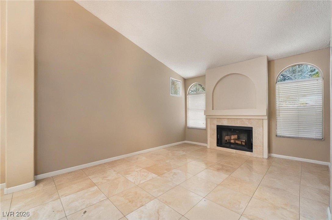 300 Redondo Street Henderson, NV 89014 - Photo 13 of 29 Unfurnished living room with a fireplace, lofted ceiling, and light tile patterned floors