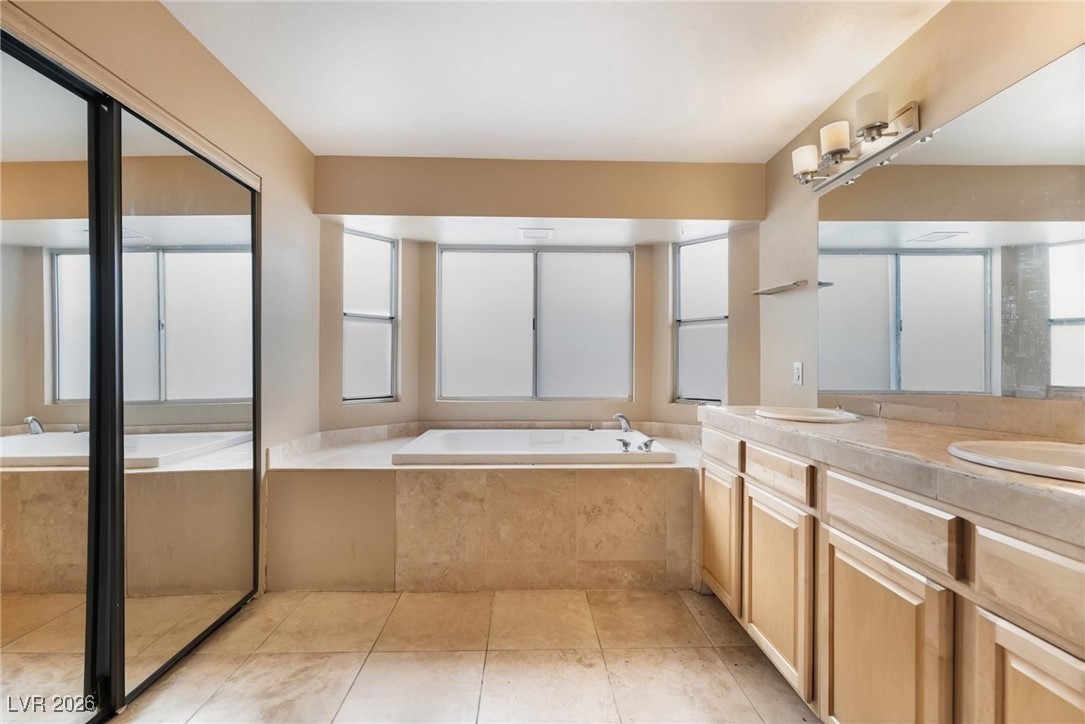 300 Redondo Street Henderson, NV 89014 - Photo 16 of 29 Full bath with a garden tub, double vanity, a shower stall, and light tile patterned floors