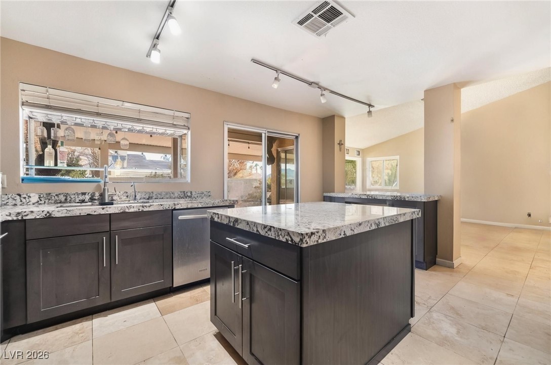 300 Redondo Street Henderson, NV 89014 - Photo 5 of 29 Kitchen with rail lighting, healthy amount of natural light, a kitchen island, light stone counters, and lofted ceiling