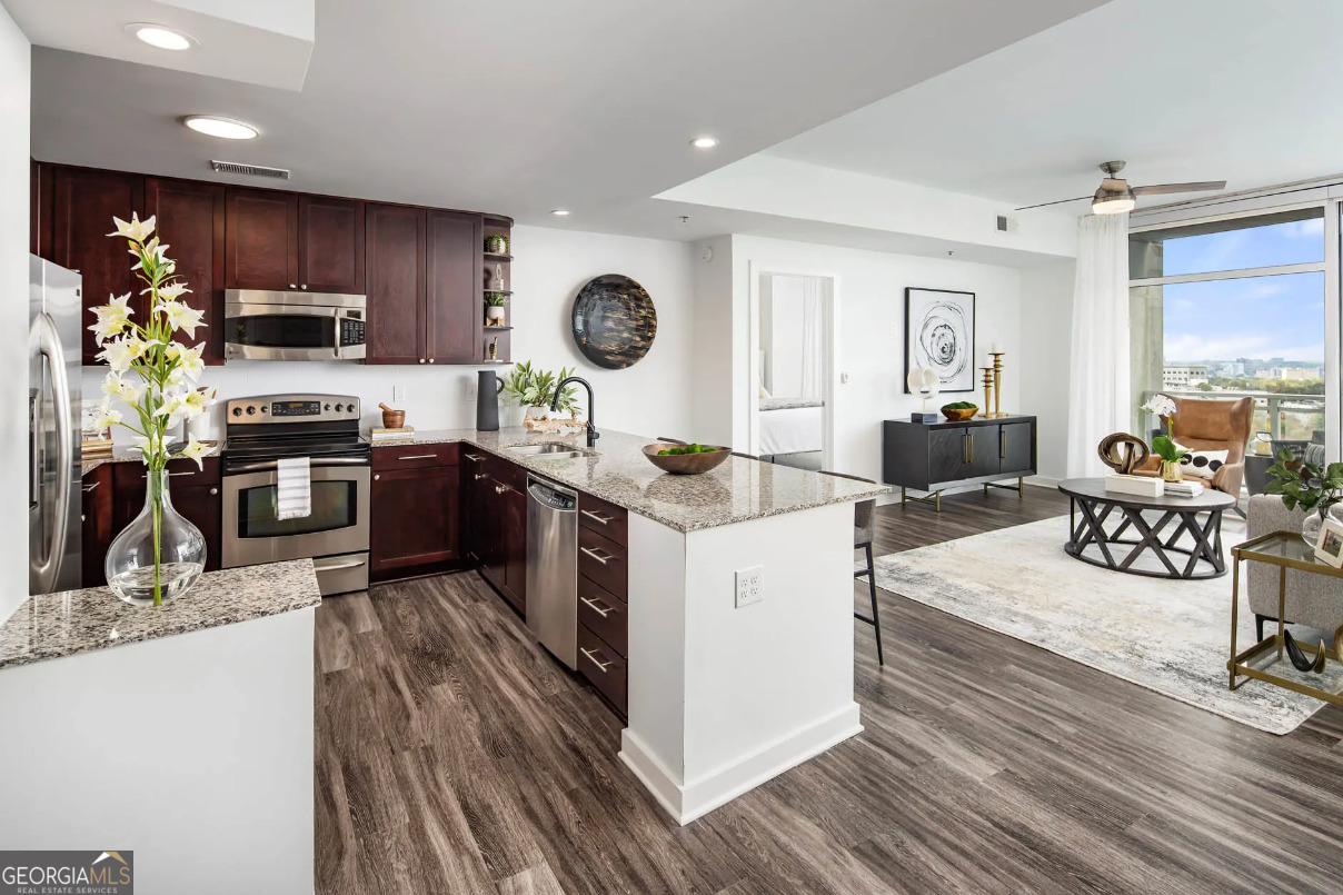 3242 Peachtree Road Northeast, Unit 1408 Atlanta, GA 30305 - Photo 13 of 41 a kitchen with stainless steel appliances granite countertop a stove top oven a sink dishwasher a dining table and chairs with wooden floor