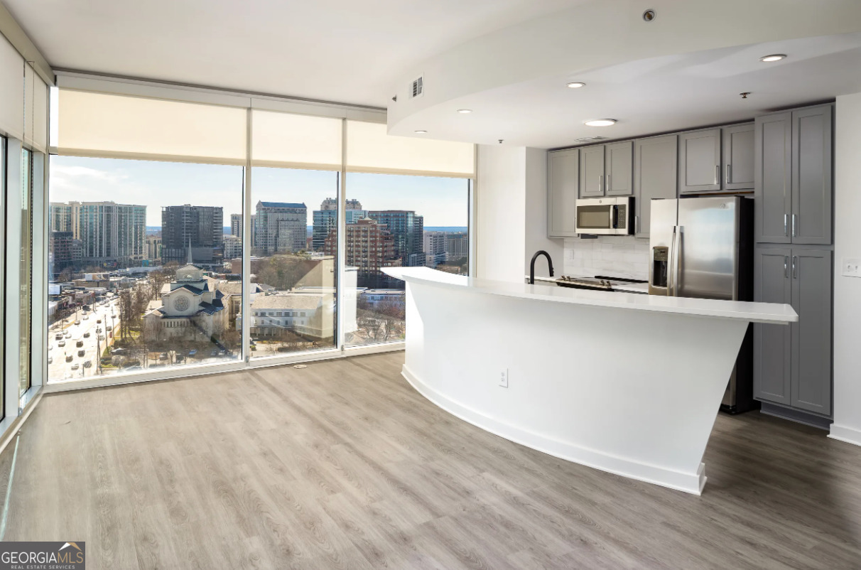 3242 Peachtree Road Northeast, Unit 1408 Atlanta, GA 30305 - Photo 3 of 41 a large kitchen with kitchen island a large window a sink and a counter top space