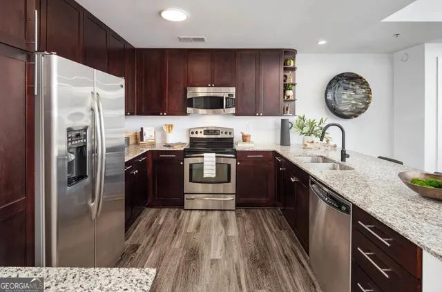 a large kitchen with stainless steel appliances a large counter top and a wooden floors