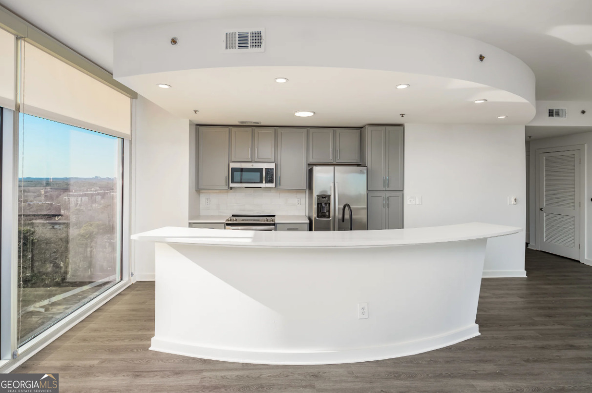 3242 Peachtree Road Northeast, Unit 1408 Atlanta, GA 30305 - Photo 7 of 41 a large kitchen with stainless steel appliances a large counter top and a wooden floors
