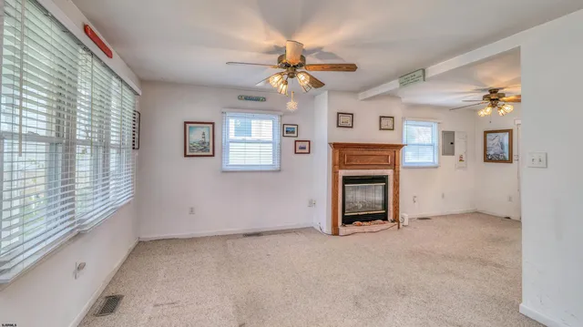 a view of a livingroom with a fireplace a ceiling fan and windows
