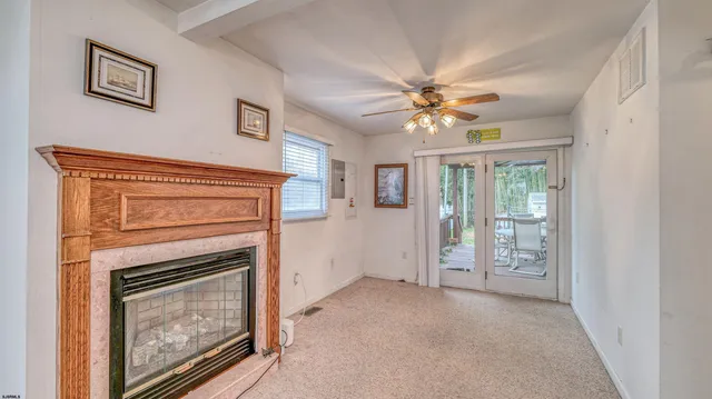 a view of an empty room with chandelier fan and fire place
