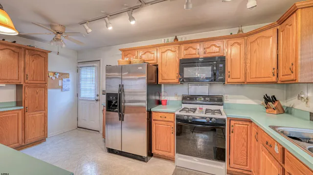 a kitchen with stainless steel appliances granite countertop a refrigerator a stove and a sink