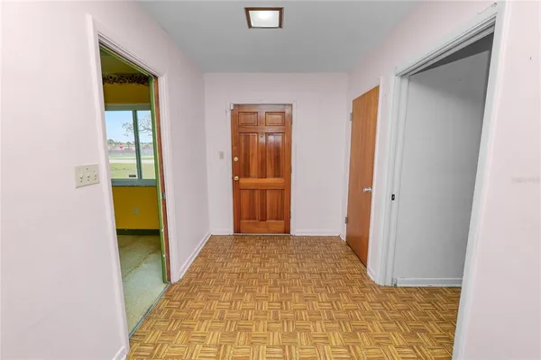 a view of a hallway with wooden floor and a kitchen
