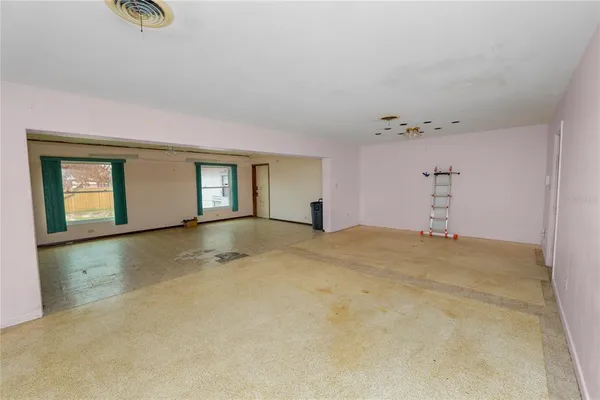 an empty room with windows and ceiling fan