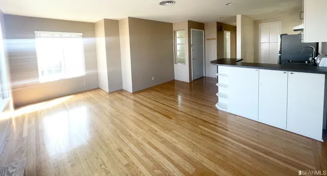 a view of a big room with wooden floor and windows
