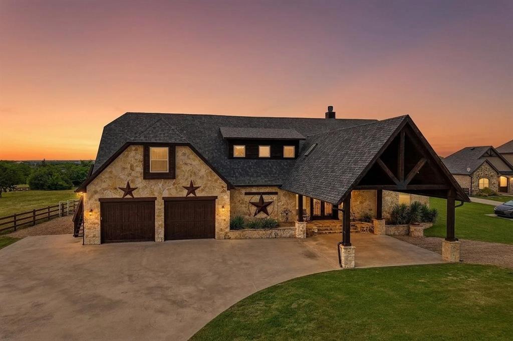 2085 Switzer Road Sanger, TX 76266 - Photo 3 of 39 Virtual twilight - Stone-clad exterior featuring a prominent porte-cochère with exposed wood beams, a two-car garage with dark wood doors, and a concrete driveway