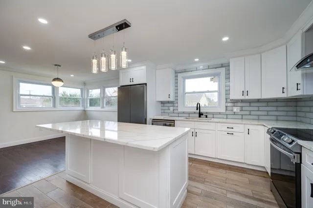 a kitchen with stainless steel appliances a sink a stove a refrigerator cabinets and a dining table